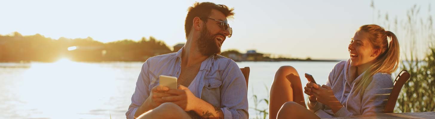 Couple laughing while sitting by a lake