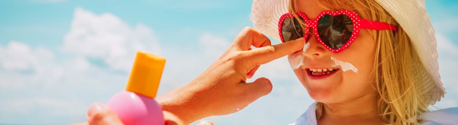 Child having suntan lotion applied