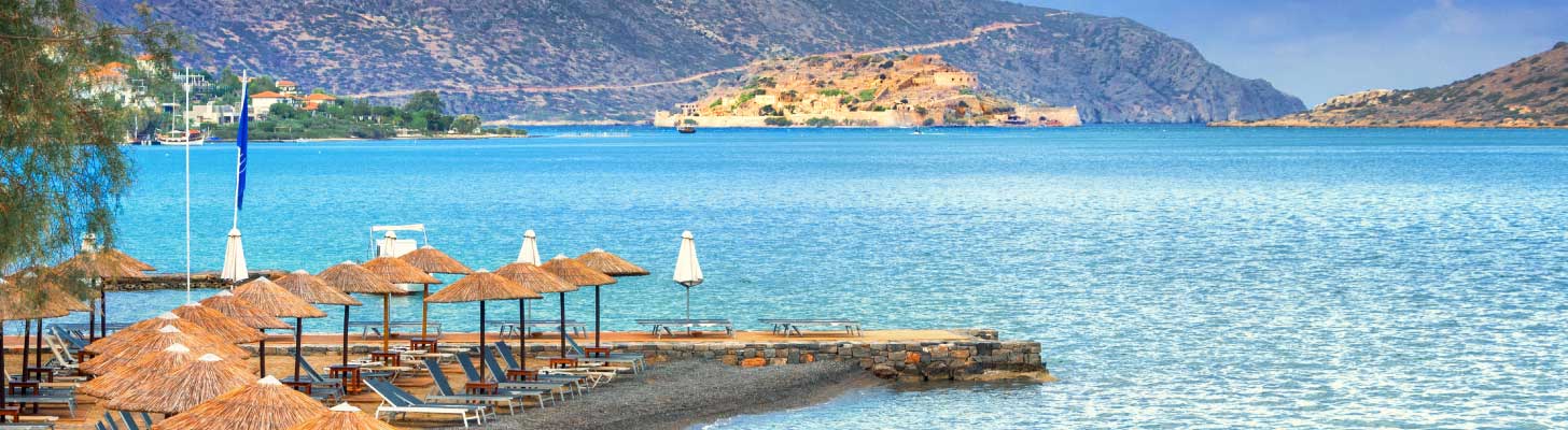 Sun umbrellas & loungers on the beach at Elounda, Crete
