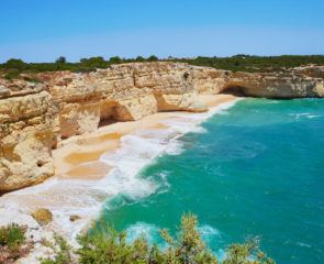 A beautiful sunny beach in the Algarve surrounding by limestone cliffs and the Atlantic Ocean