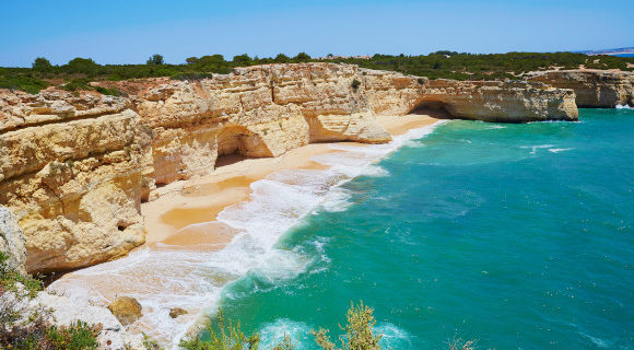 A beautiful sunny beach in the Algarve surrounding by limestone cliffs and the Atlantic Ocean