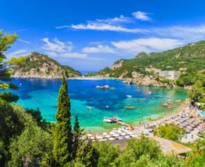 The breathtaking Palaiokastritsa Beach on the island of Corfu, surrounded by vast greenery and lined with sunloungers