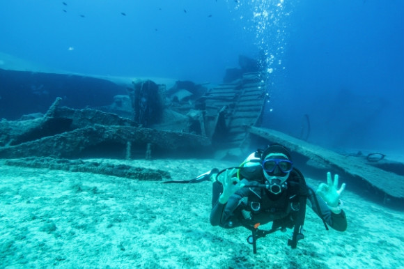 Woman scuba diving the underwater world surrounded by old ruins on the ocean floor