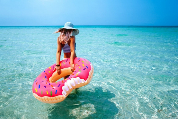 Woman dragging an inflatable pink donut into the Caribbean sea