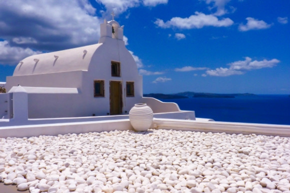 The pebbled grounds of a white church in Perissa Santorini Greece