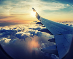 Views of the aeroplane wing and puffy white clouds from the plane window.