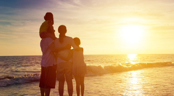 Family huddled together on the beach watching the beautiful sunset over the ocean
