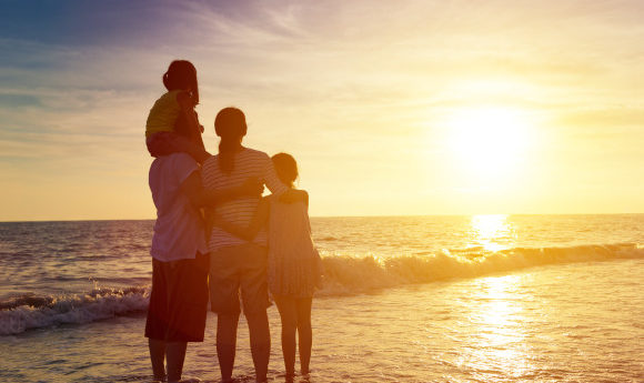 Family huddled together on the beach watching the beautiful sunset over the ocean