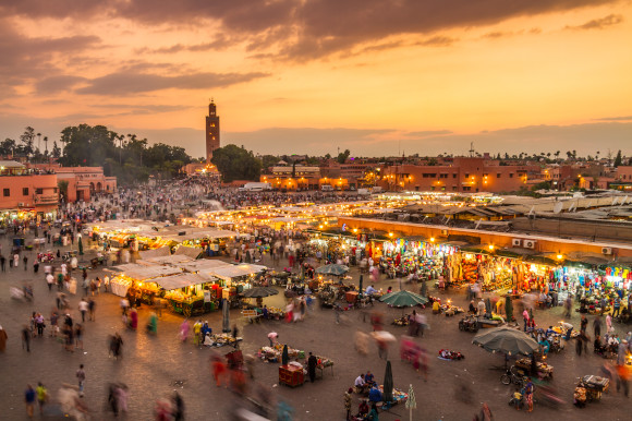A busy Jamaa el Fna market square in Marrakech at sunset with lit-up stalls