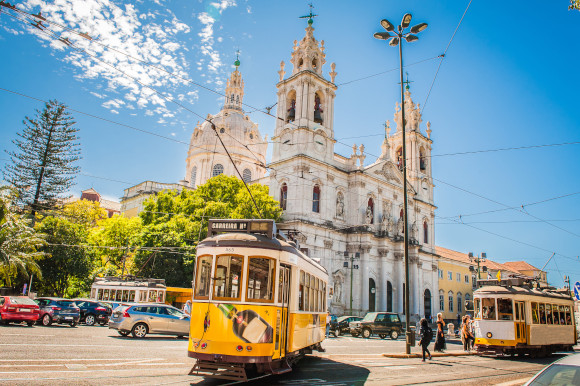 Stunning day time views of Lisbon Cathedral and the old tram transportation in the busy city centre in Portugal