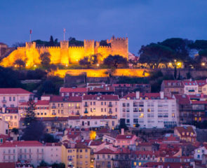 Lisbon's skyline at night with a lit-up castle perched high up on the hillside