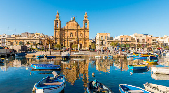 Malta Sliema town and its waterfront with floating boats and views of the dominating cathedral