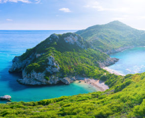 Beautiful summertime panoramic seascape. View of the cliff into the crystal clear azure sea bay and distant islands. Unique secluded beach. Agios Stefanos cape. Afionas. Corfu. Greece.