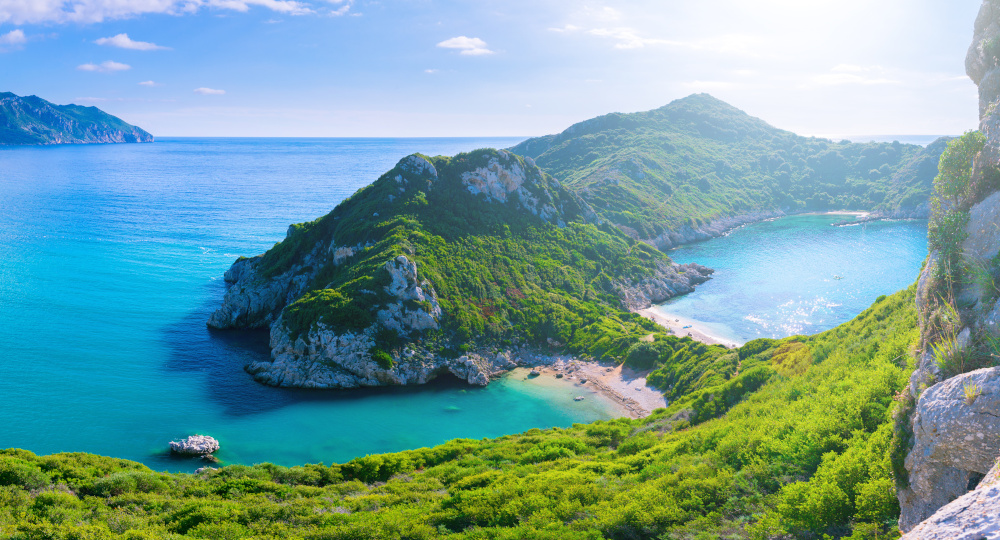 Beautiful summertime panoramic seascape. View of the cliff into the crystal clear azure sea bay and distant islands. Unique secluded beach. Agios Stefanos cape. Afionas. Corfu. Greece.