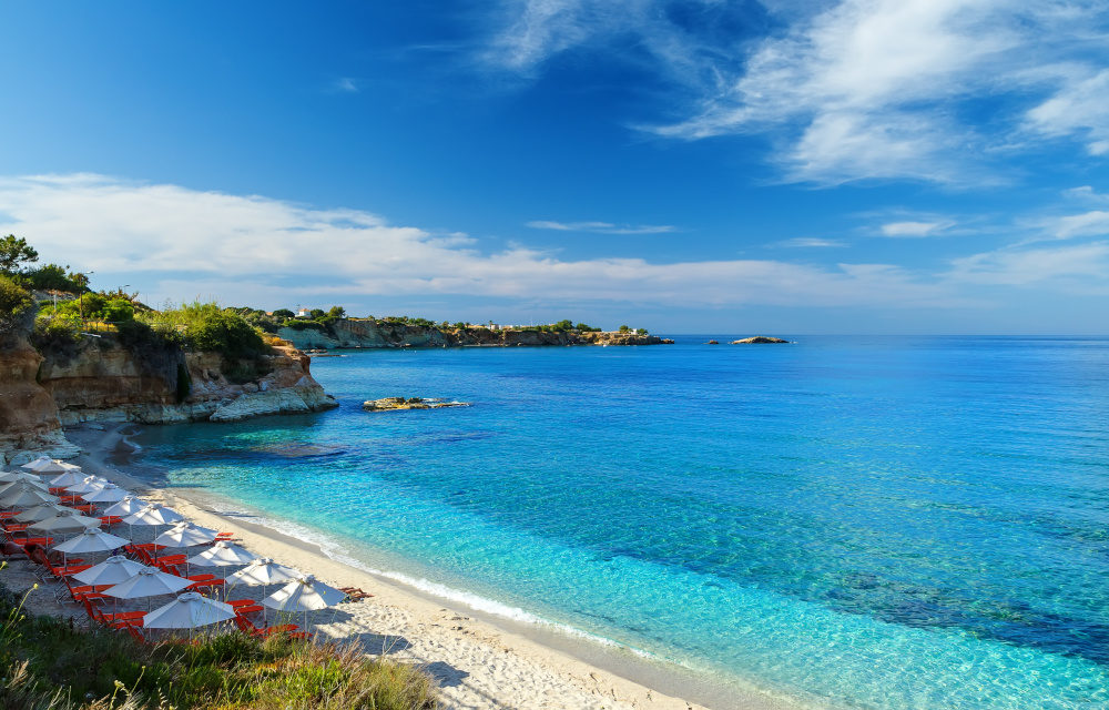 beach with white sand and clear blue water in a beautiful Bay with sun beds and umbrellas, Crete, Greece