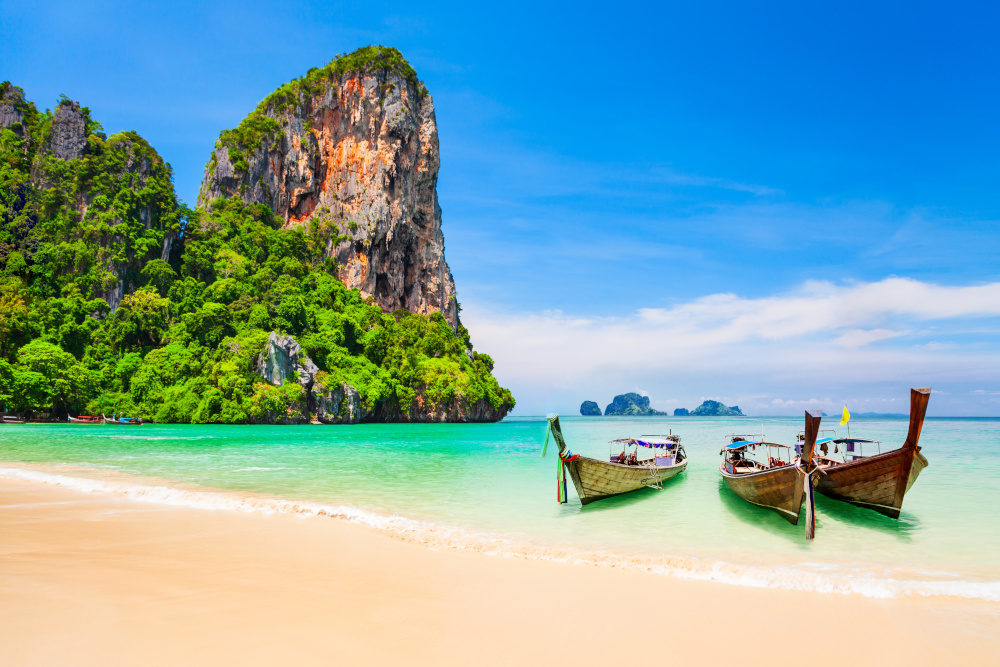 Boats at the beauty beach with limestone cliff and crystal clear water in Thailand