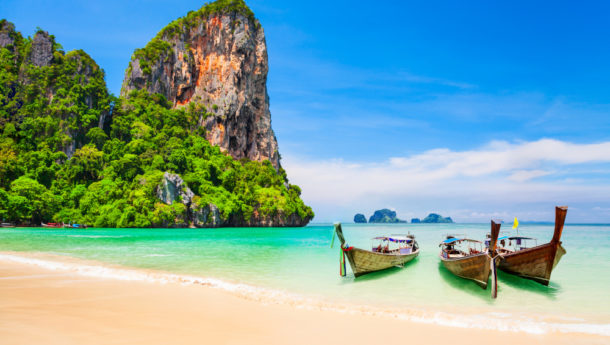 Boats at the beauty beach with limestone cliff and crystal clear water in Thailand