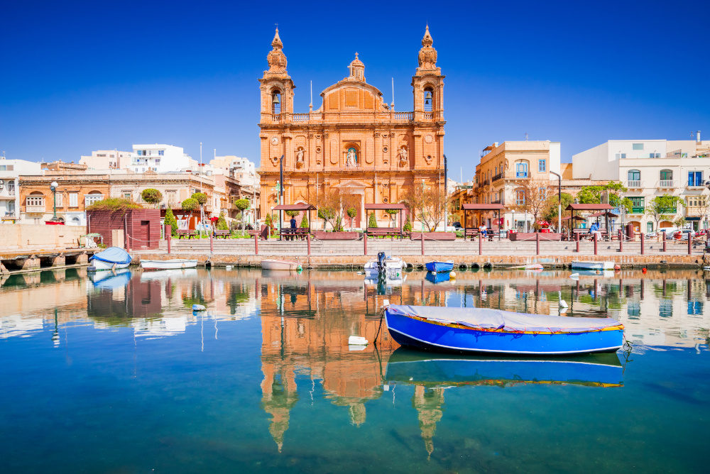 Valletta, Malta. Msida Marina boat and church reflection into water.