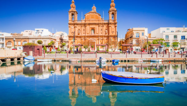 Valletta, Malta. Msida Marina boat and church reflection into water.