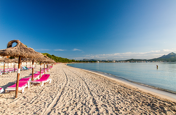 Beach on Alcudia Majorca with pink sun loungers and parasols