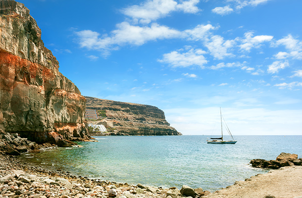Small pebble bay in Gran Canaria with boat on water