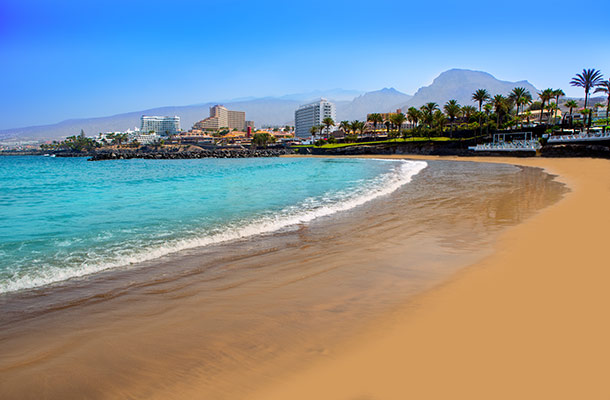 On the golden sandy beach of Playa de las Americas in Tenerife, Spain