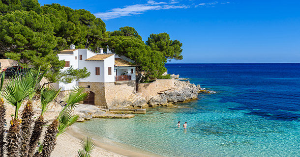 A beach in Majorca with white sand and clear blue water.