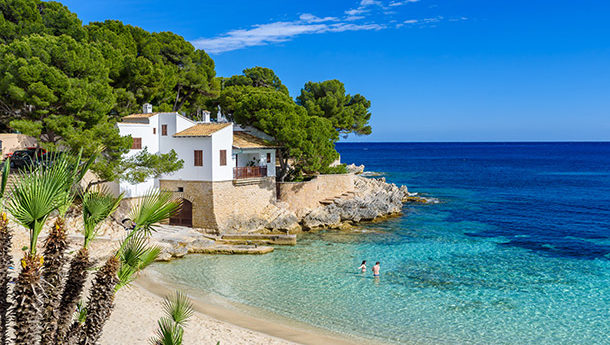 A beach in Majorca with white sand and clear blue water.