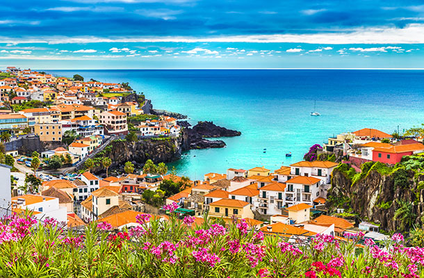 A view looking down at white houses with terracotta roofs and the bay in the background in Madeira.