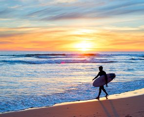 Surfer with board walking along the beach in the sunset, Algarve